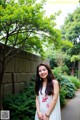 A woman standing in front of a tree in a park.