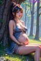 A pregnant woman sitting under a tree in a forest.