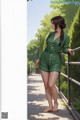 A woman in a green romper standing on a bridge.